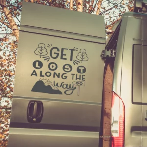 Get lost along the way sticker op de deur van een van met bergjes en boompjes ingezoomd.