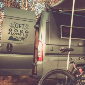 Get lost along the way sticker op de deur van een van met bergjes en boompjes.