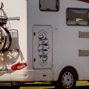 Live it up skateboard sticker afgebeeld op een camper. Het is een skateboard met een lint rond gedraaid en de tekst er op ingezoomd.